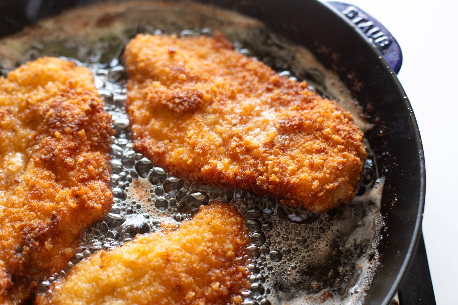 Fried breaded chicken in a skillet.