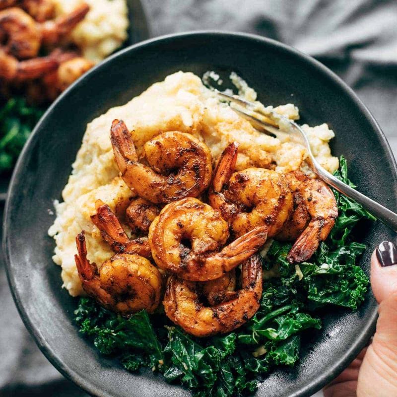 Spicy shrimp on a plate with mashed cauliflower and kale.