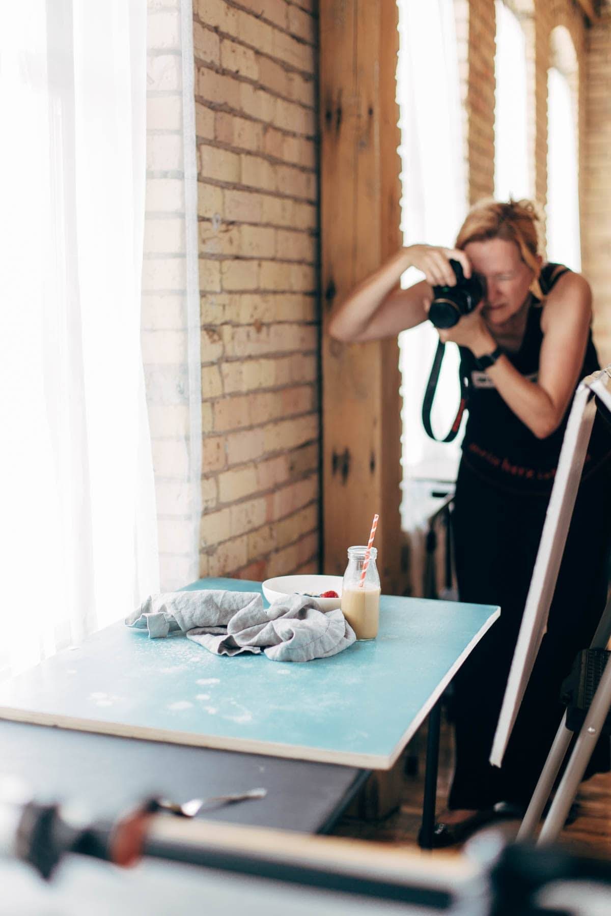Woman taking a photo of a bowl and a glass filled with coffee.