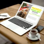A laptop on a table with a cup of coffee.