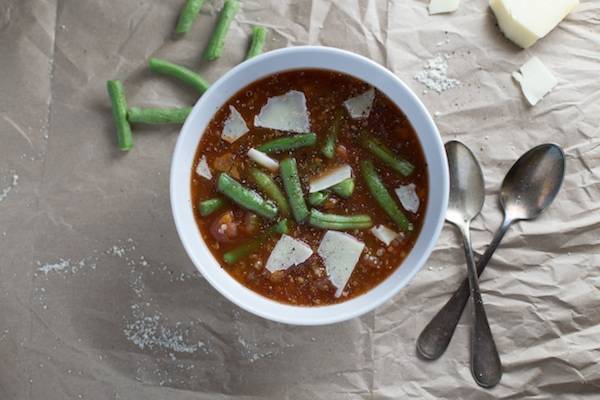 Soup in a bowl with green beans in a white bowl.