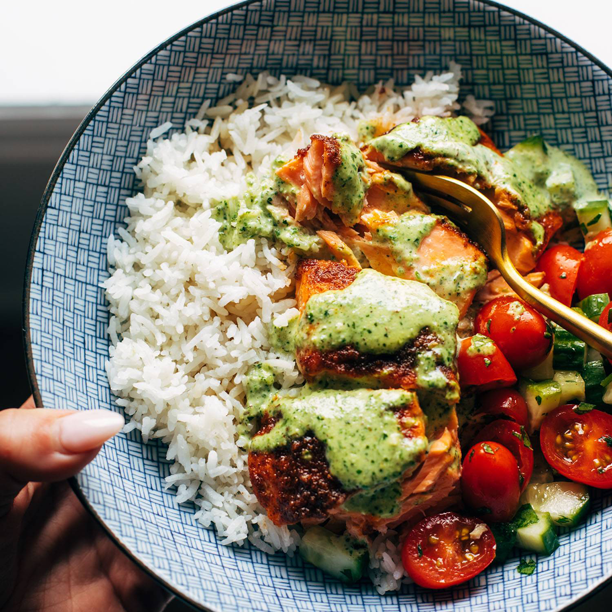 Salmon in a bowl with rice, tomato salad, and basil sauce.